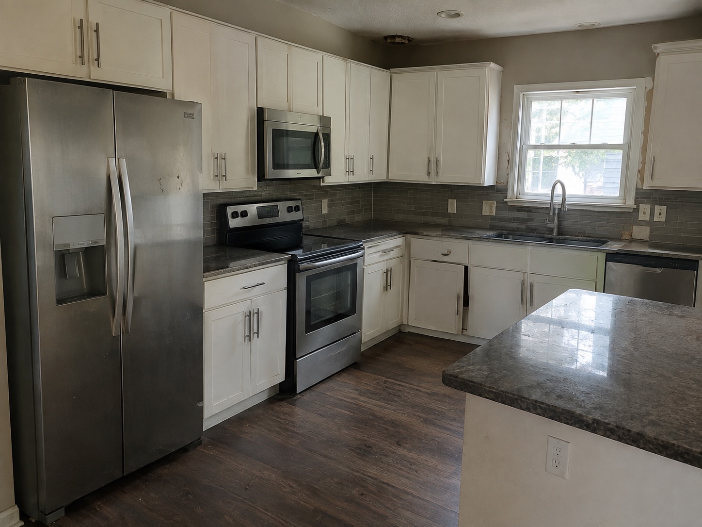The kitchen before: worn white cabinets and a dated worktop